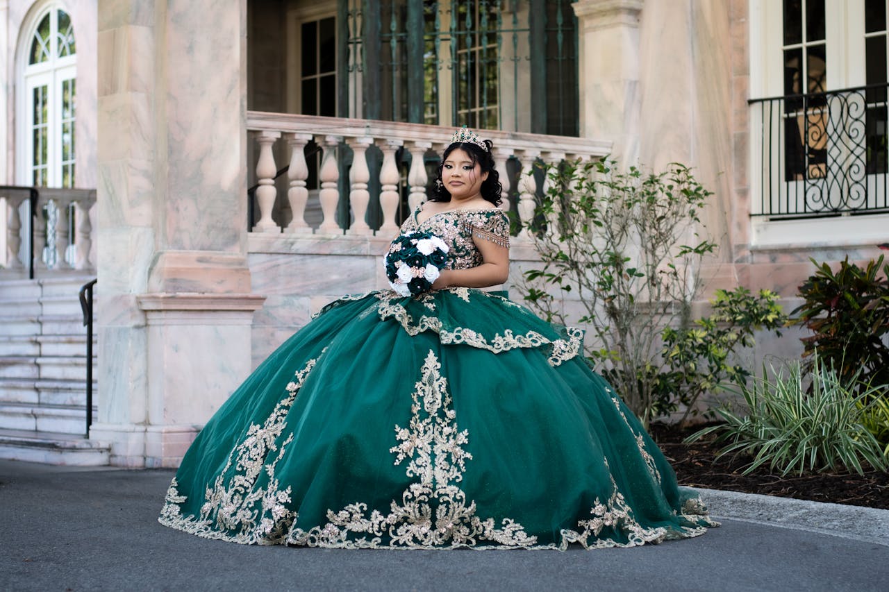 Services A quinceañera wearing a stunning green ball gown poses elegantly before a mansion in Florida.